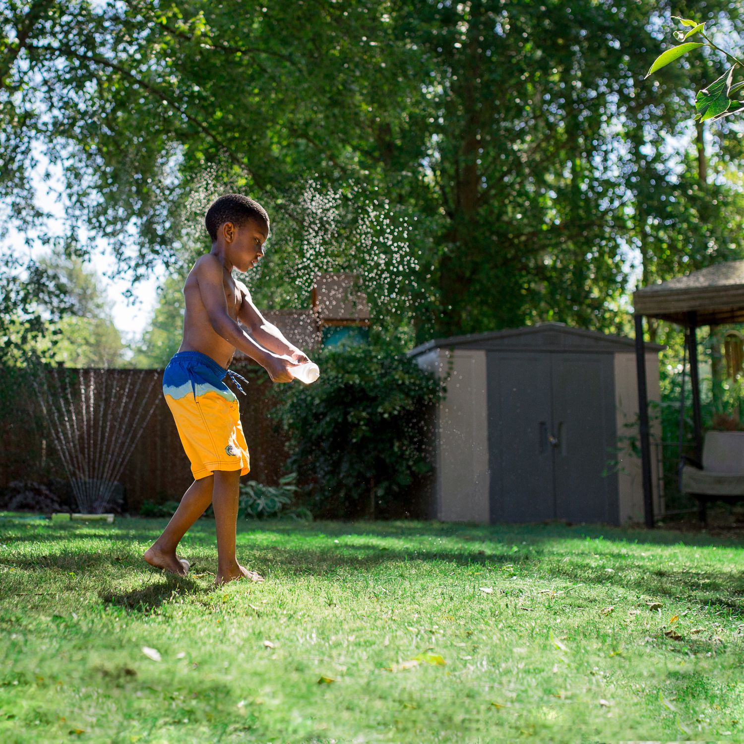 Boy playing a back yard sprinkler in summer