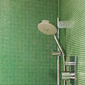 A modern bathroom with a green tile shower