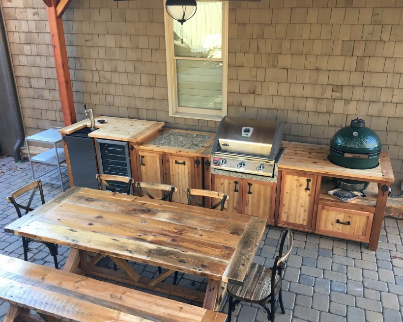 Wooden outdoor kitchen with grill, mini fridge and table