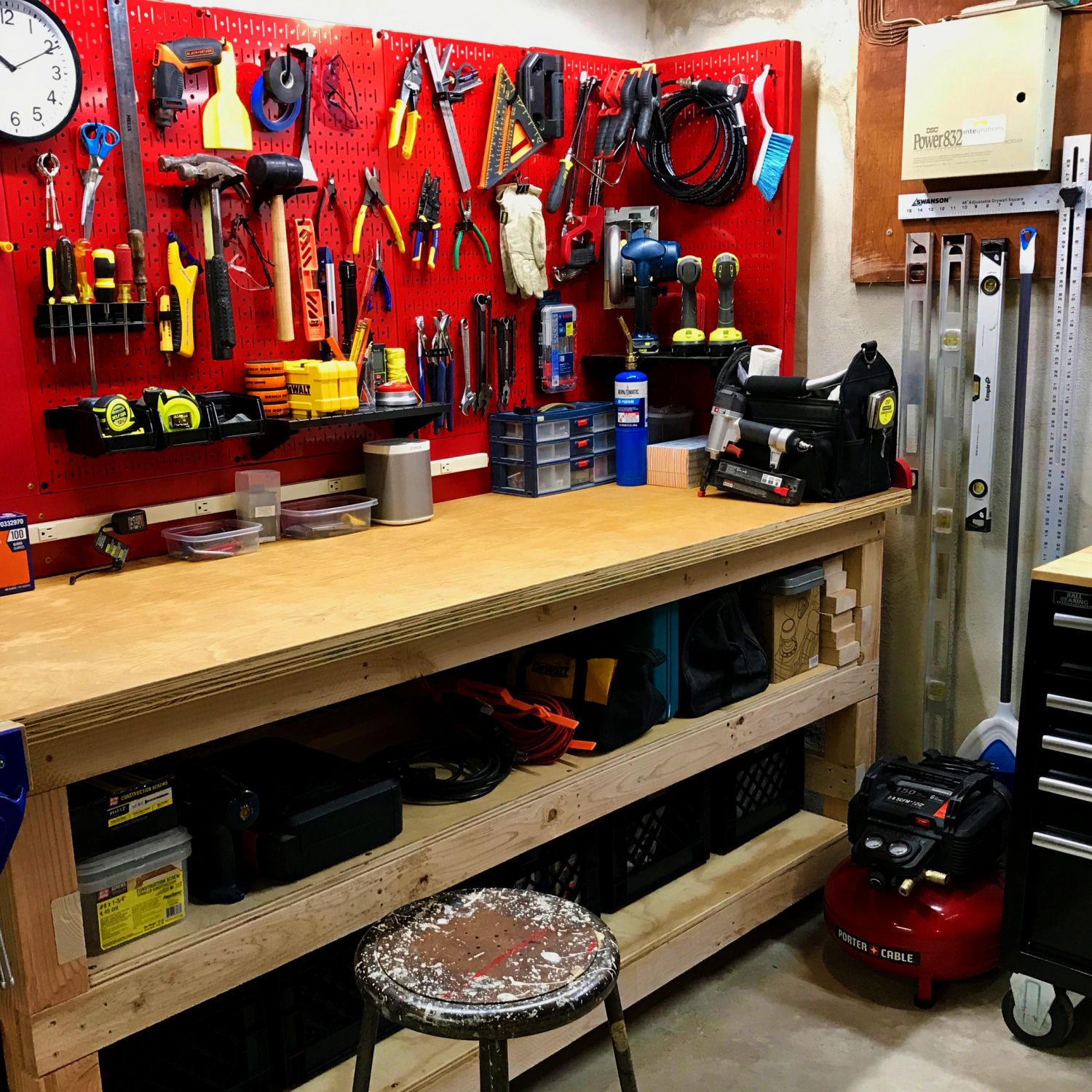 Wooden work bench with red peg board covered in tools