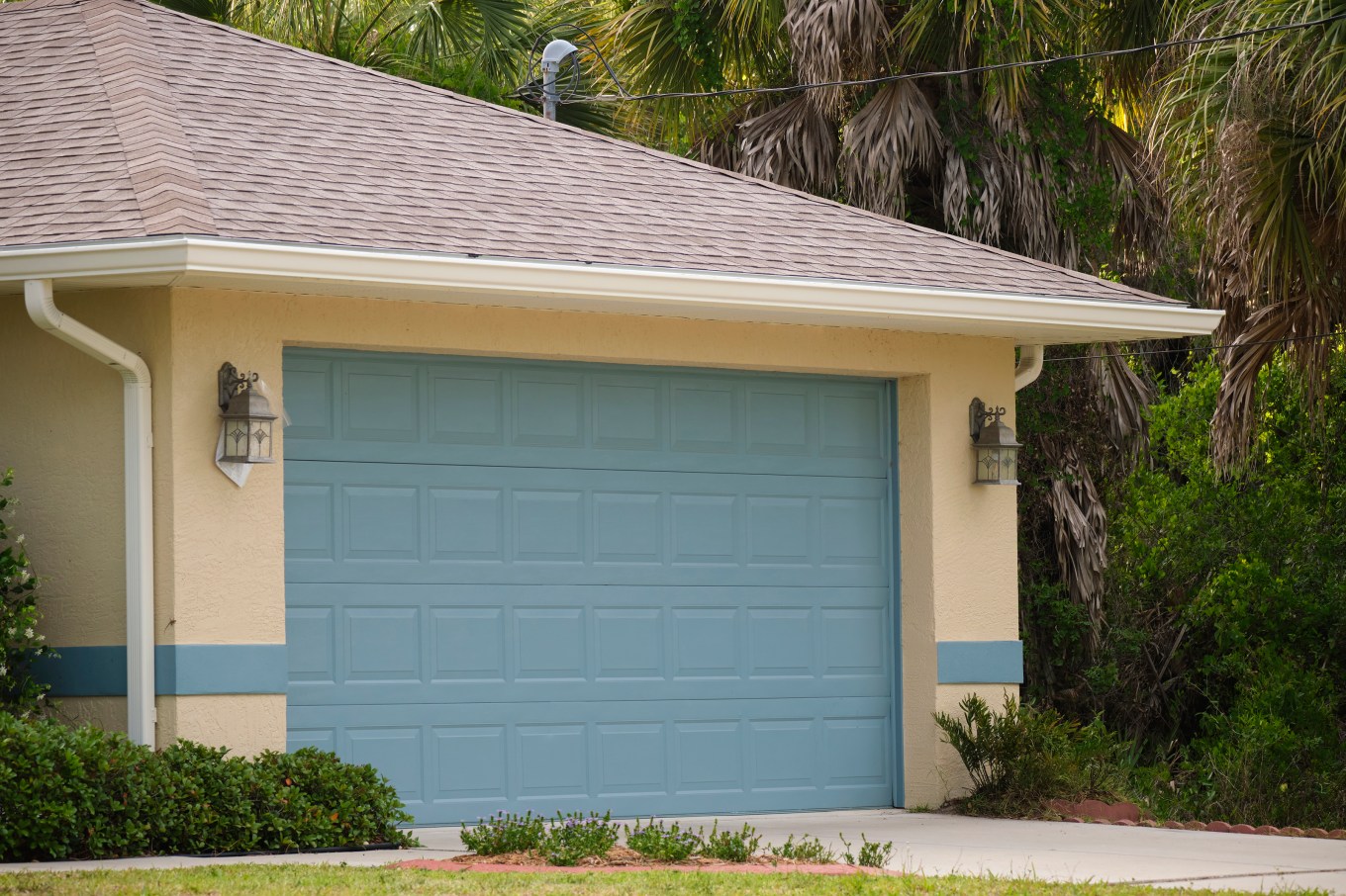 The wide garage featuring a double door and a concrete driveway of a modern house.