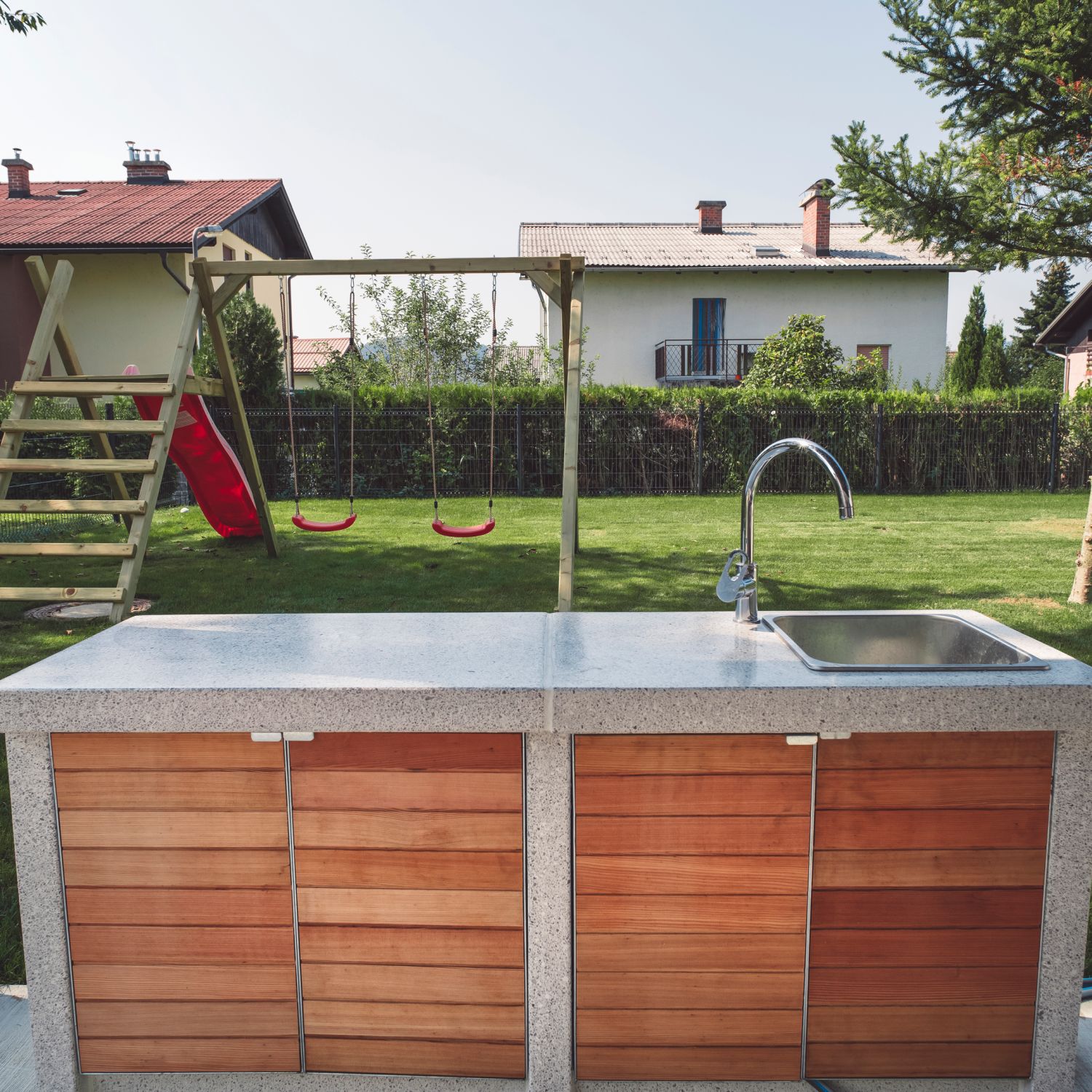 A beautiful sink sits outside as part of an outdoor kitchen under a pergola.