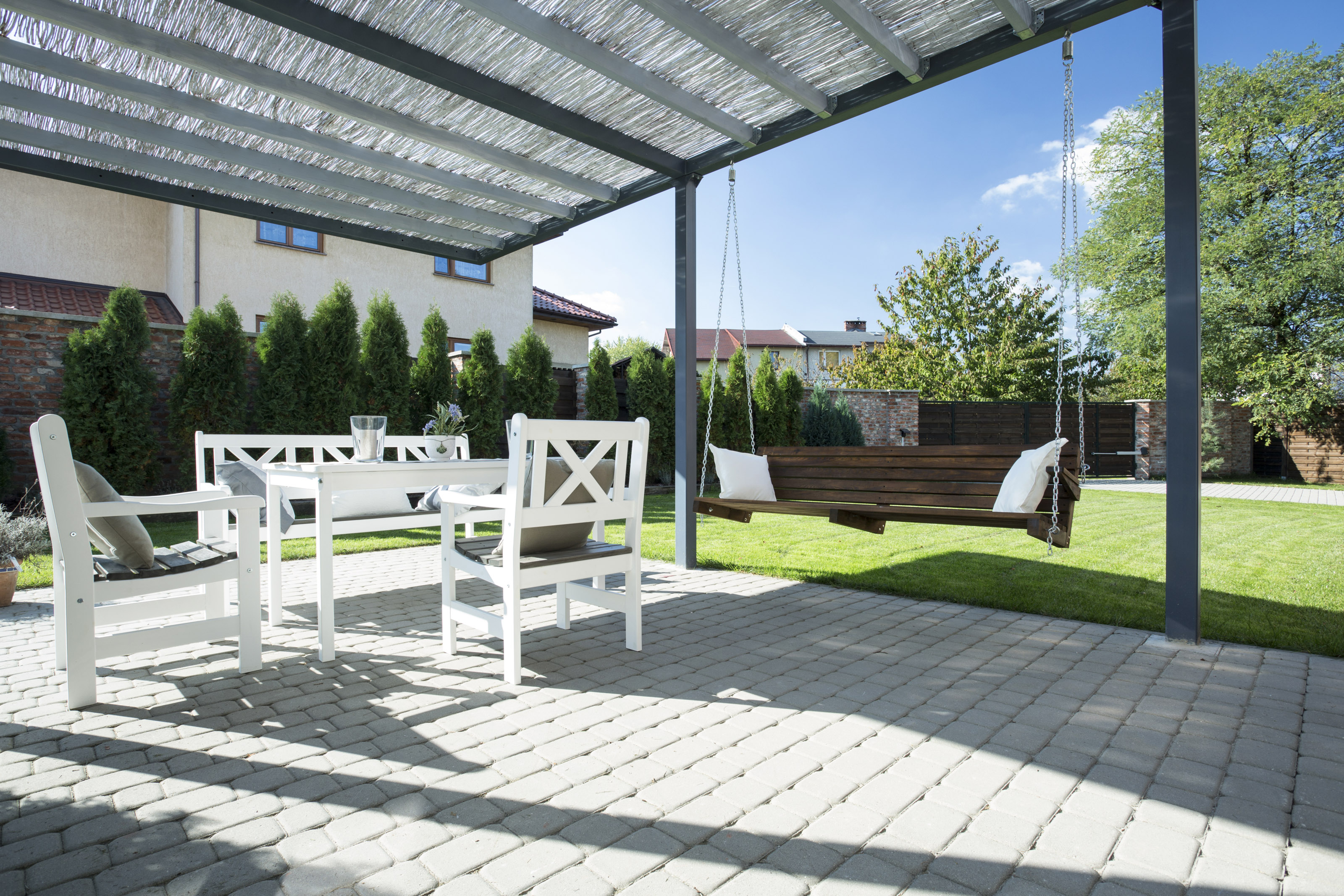 Modern bohemian pergola with patio furniture and a bench swing.