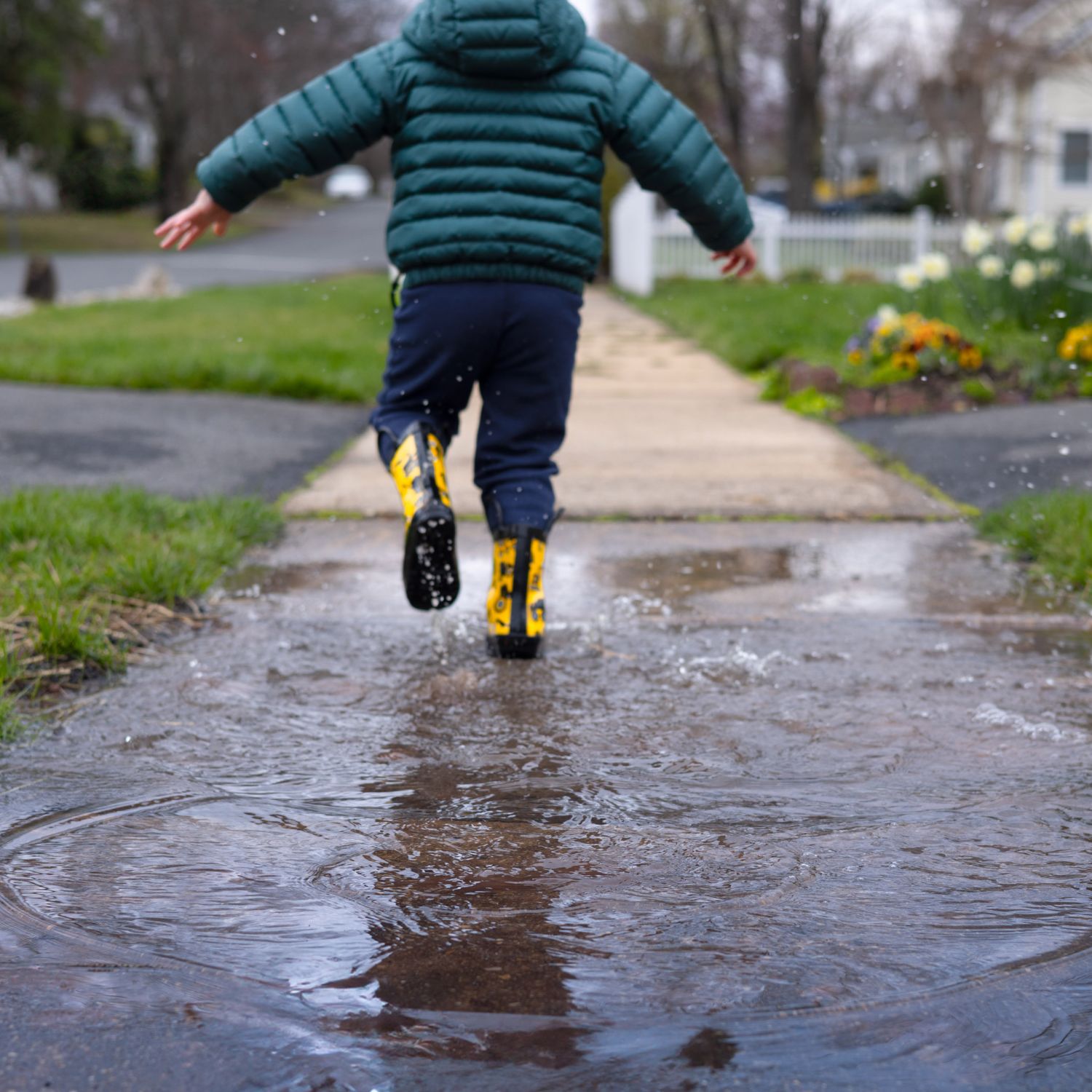 A child running through a puddle from a French drain cleaning.