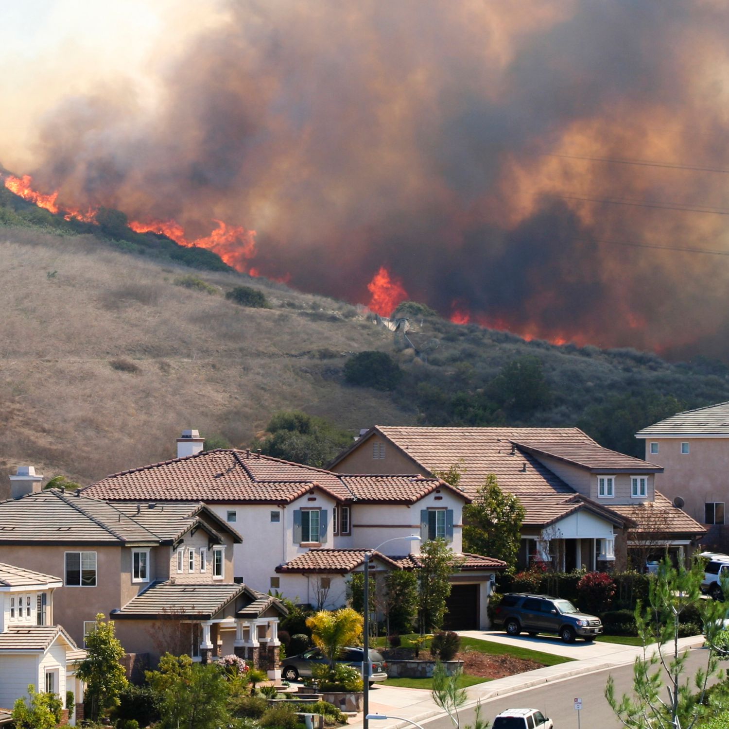 A large brush wildfire burning extremely close to several homes.