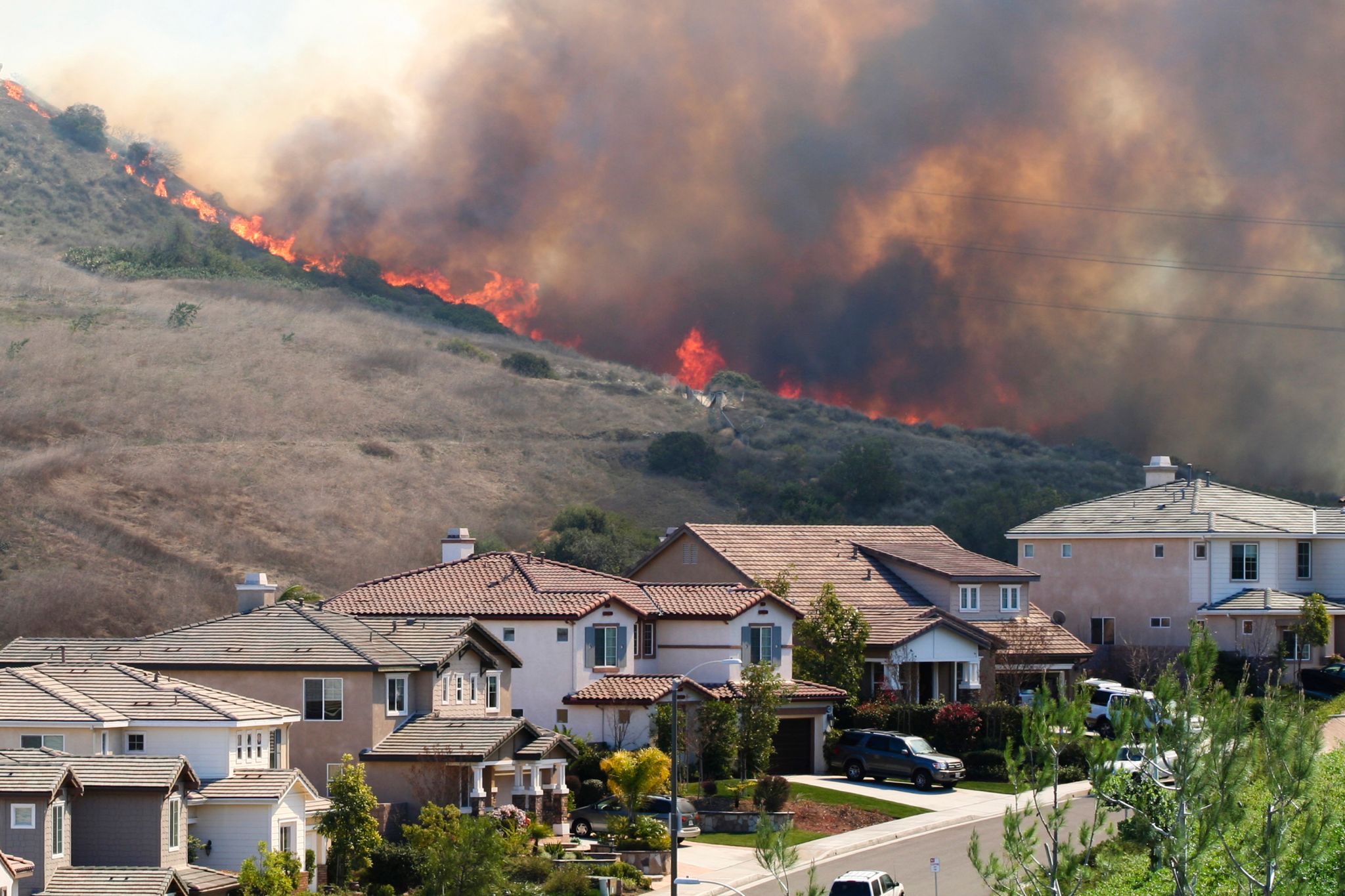 A large brush wildfire burning extremely close to several homes.