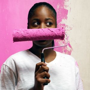 A woman holding up a pink paint roller.