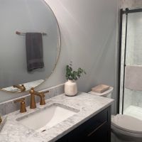 A remodeled, refreshed modern bathroom with considerable shower space and refinished countertops.