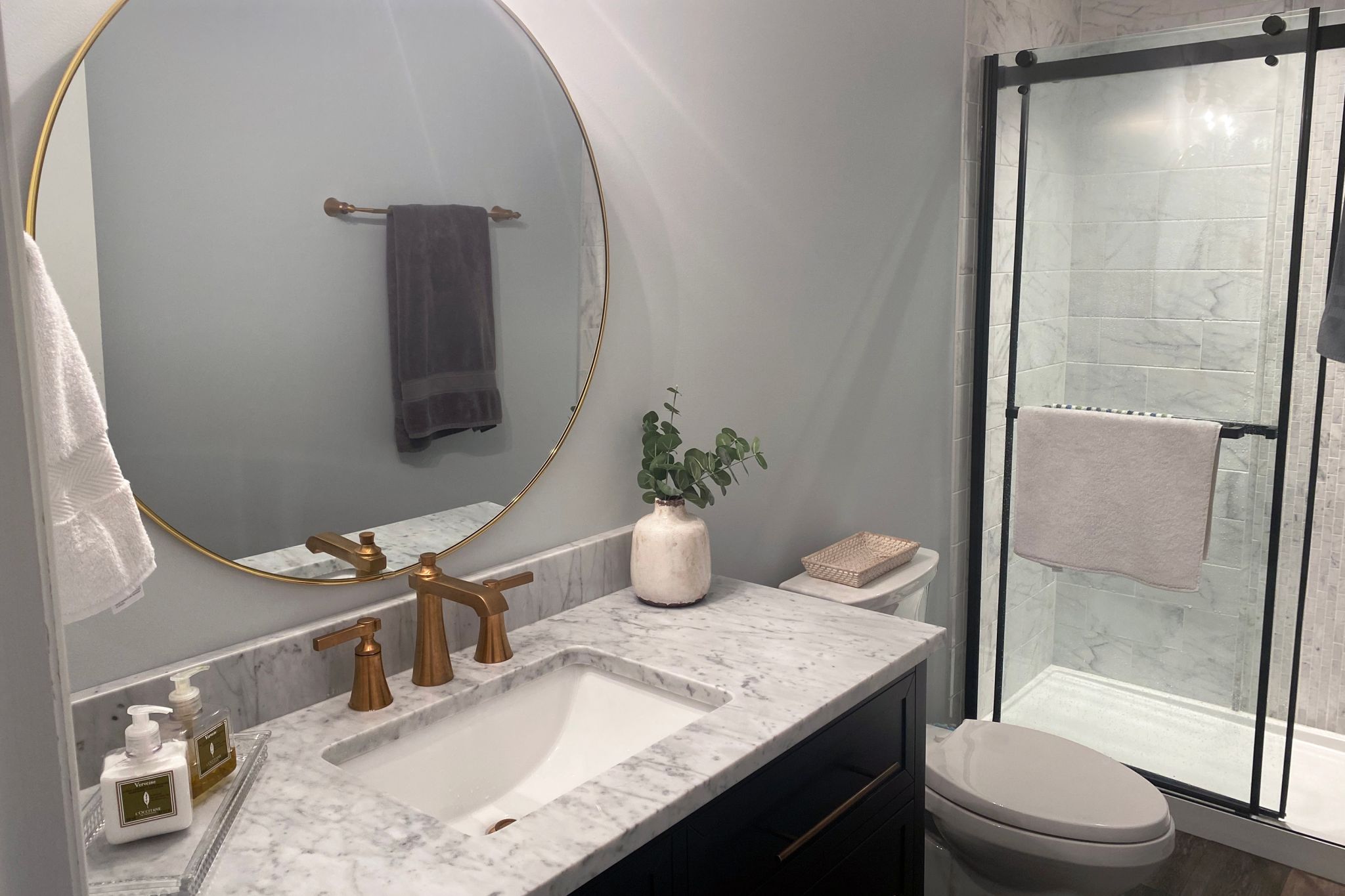 A remodeled, refreshed modern bathroom with considerable shower space and refinished countertops.