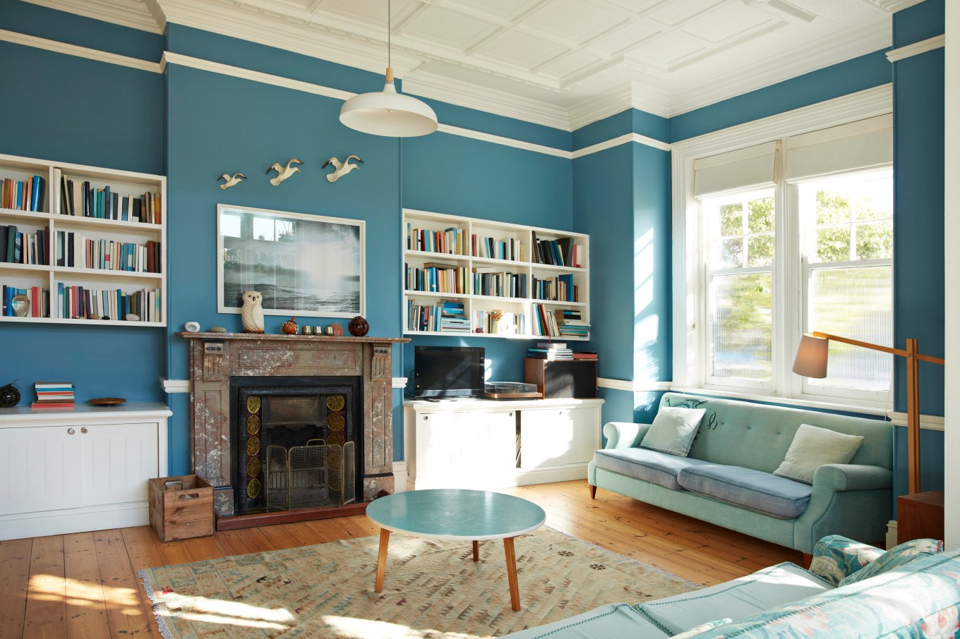 A freshly painted bright living room with a bookshelf and fireplace.