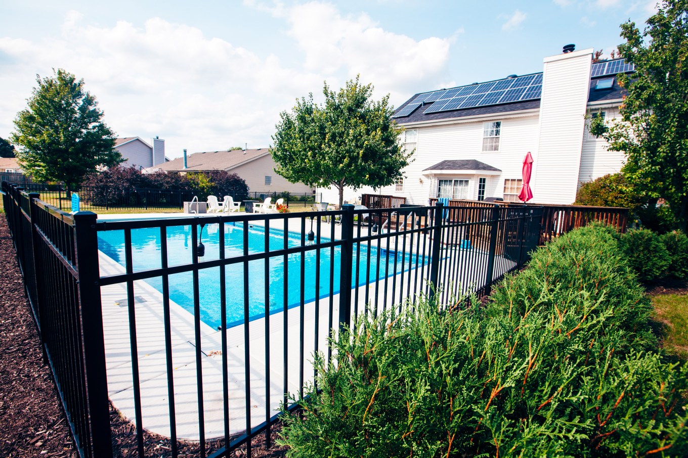 A beautiful backyard pool surrounded by an aluminum fence.