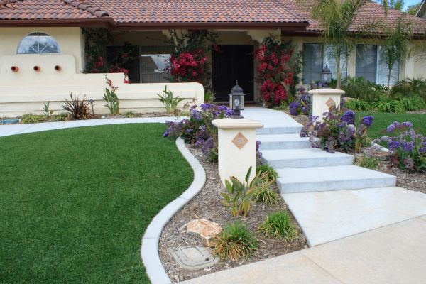 A shot of a gorgeous front yard with artificial grass on either side of a walkway.