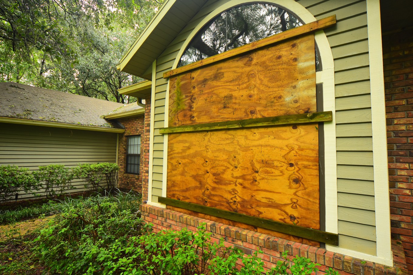 Home with plywood and planks over large windows in an attempt to block high winds and flying debris from a hurricane.