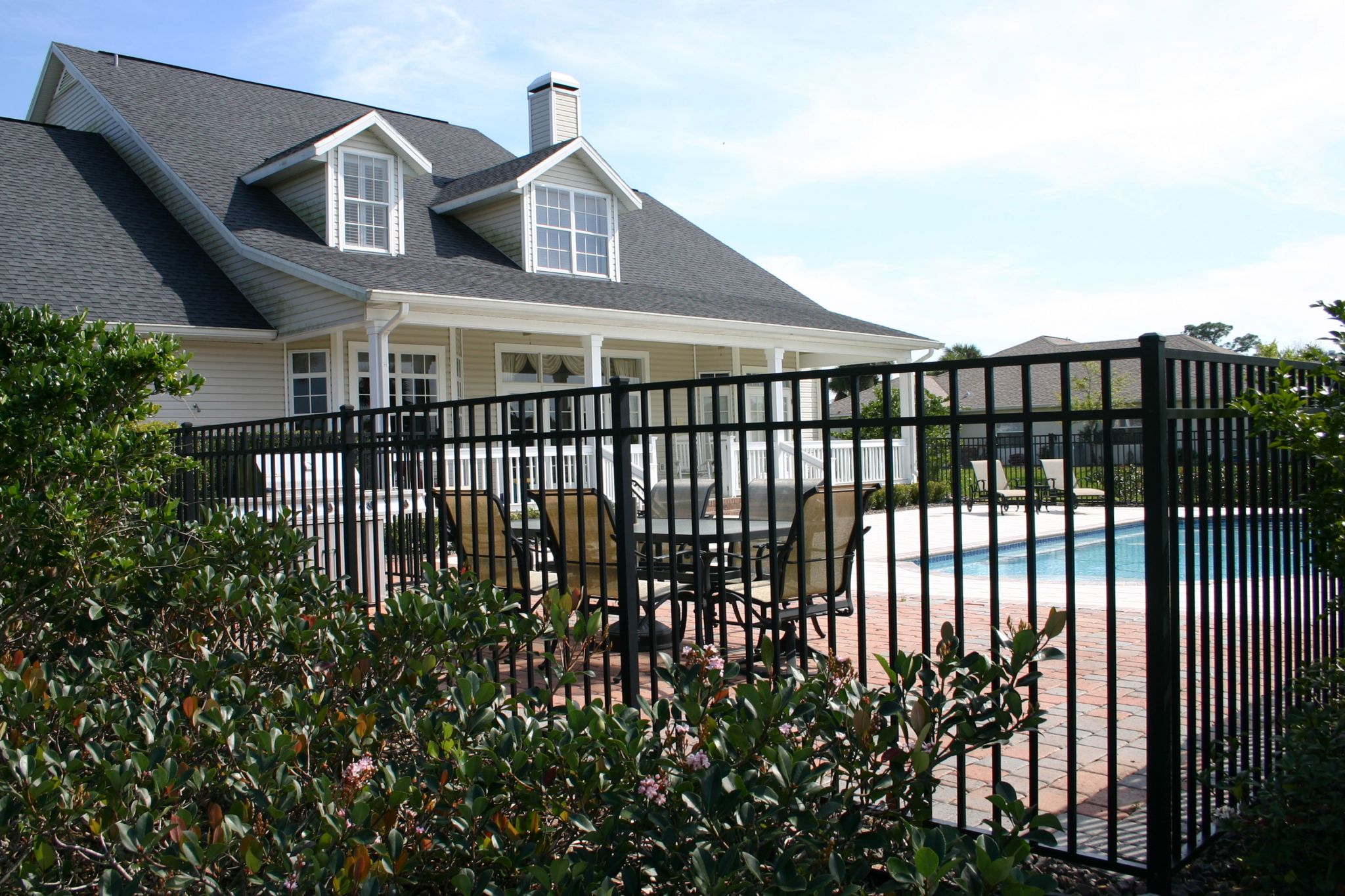 A beautiful suburban home with a fence around a backyard pool.