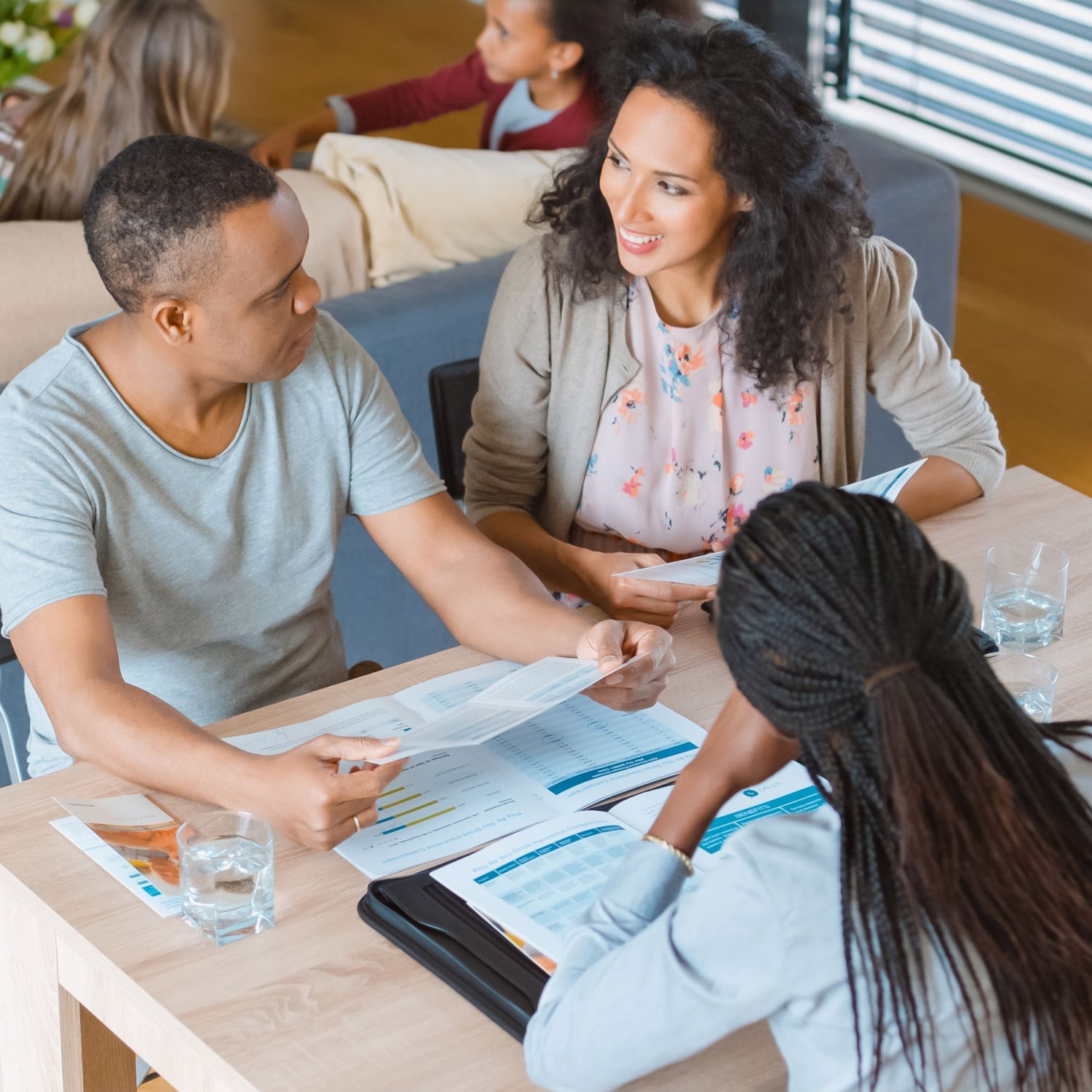 A couple with two children meeting with a real estate agent to help them sell their home.