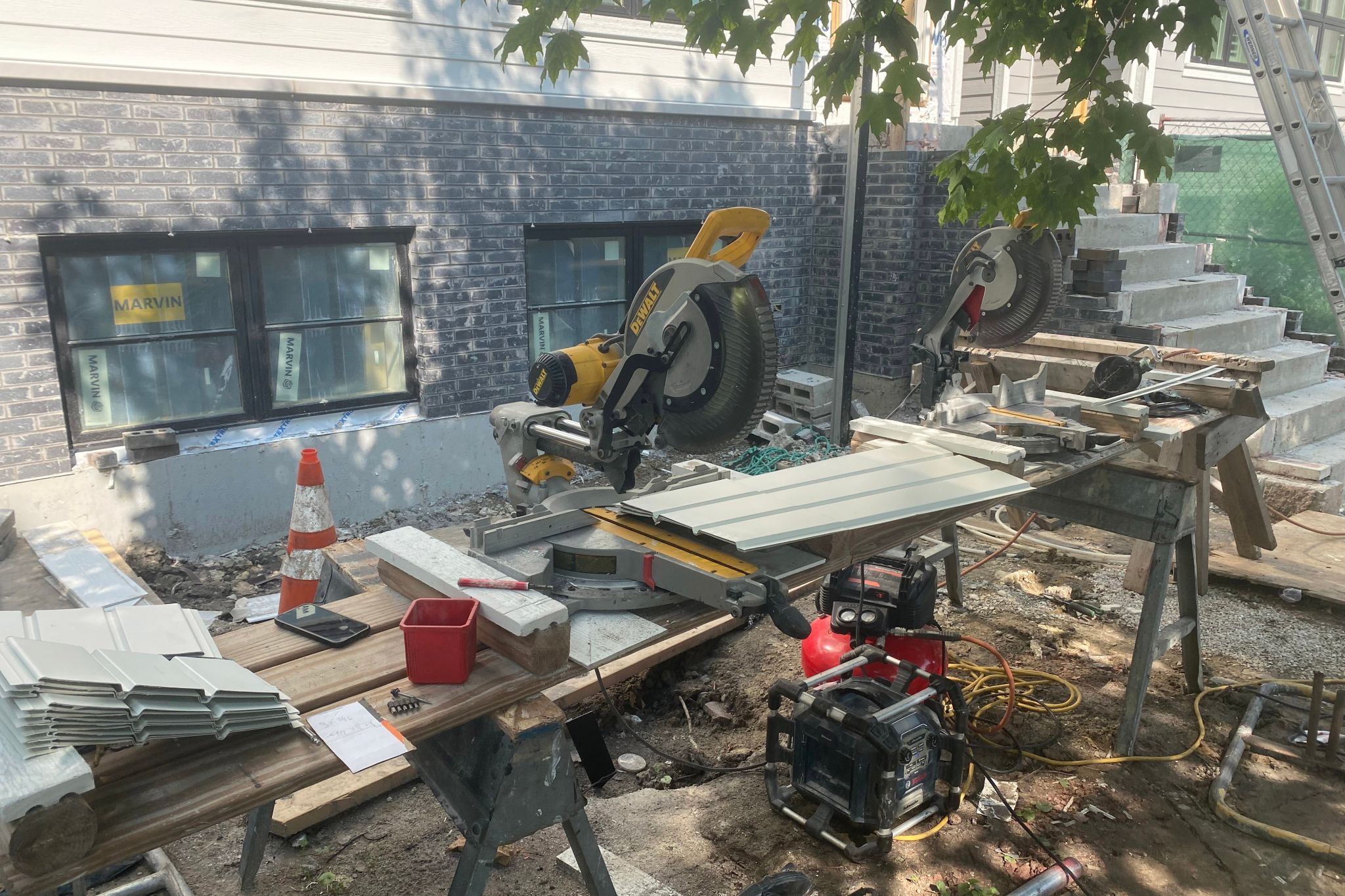 Image of a building with its siding being replaced. New siding is visible on workbenches.