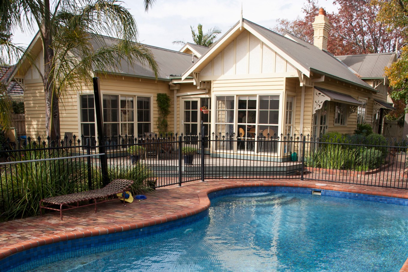 The backyard of a house with a wrought iron fence for safety.