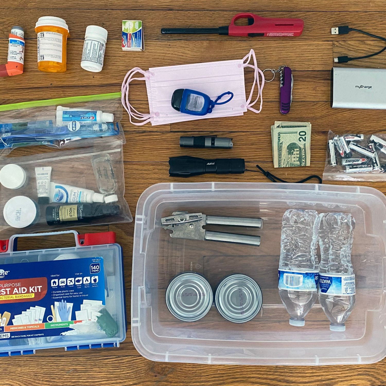 An emergency preparedness kit with a variety of important items in it like pills, a flashlight, first aid kit, batteries, money, and more.