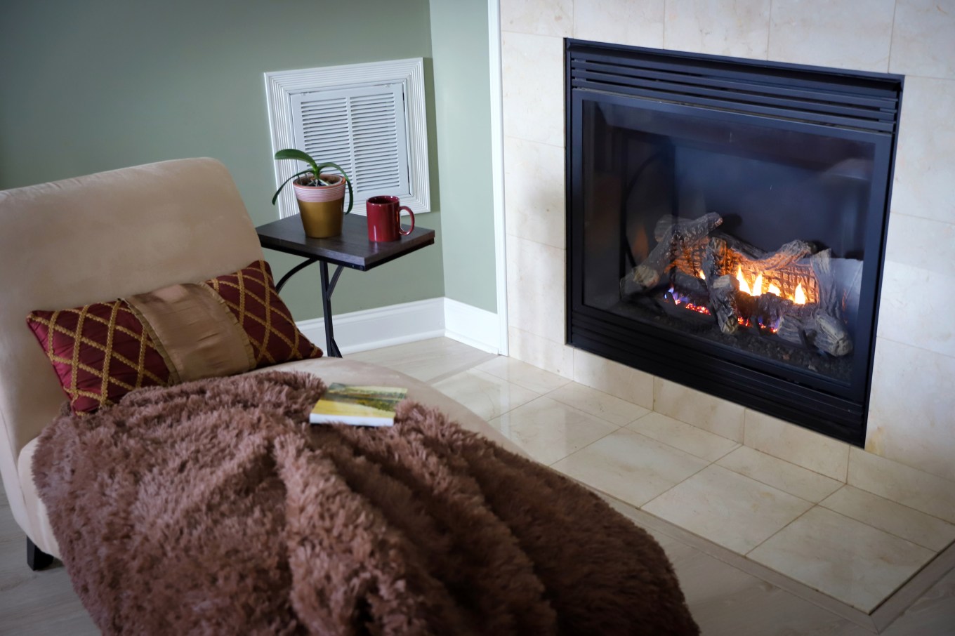 Cozy and warm chaise by traditional gas fireplace in master bedroom.