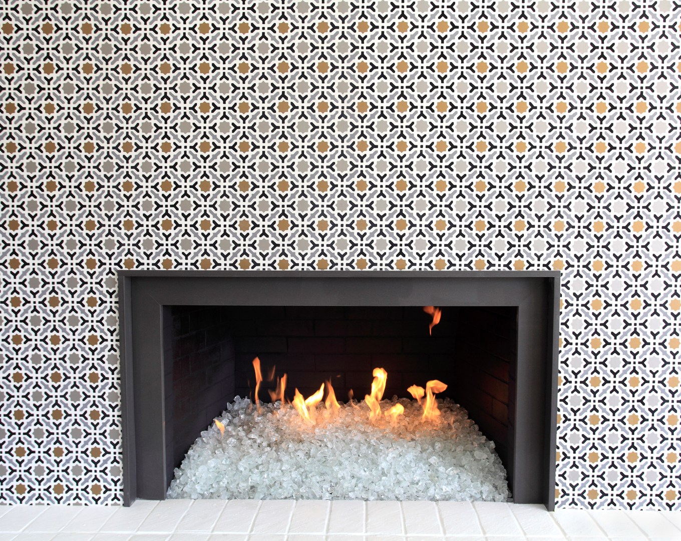 Clear Glass stones in the modern gas fireplace. Dancing flames,black metal fireplace with Wallpaper.