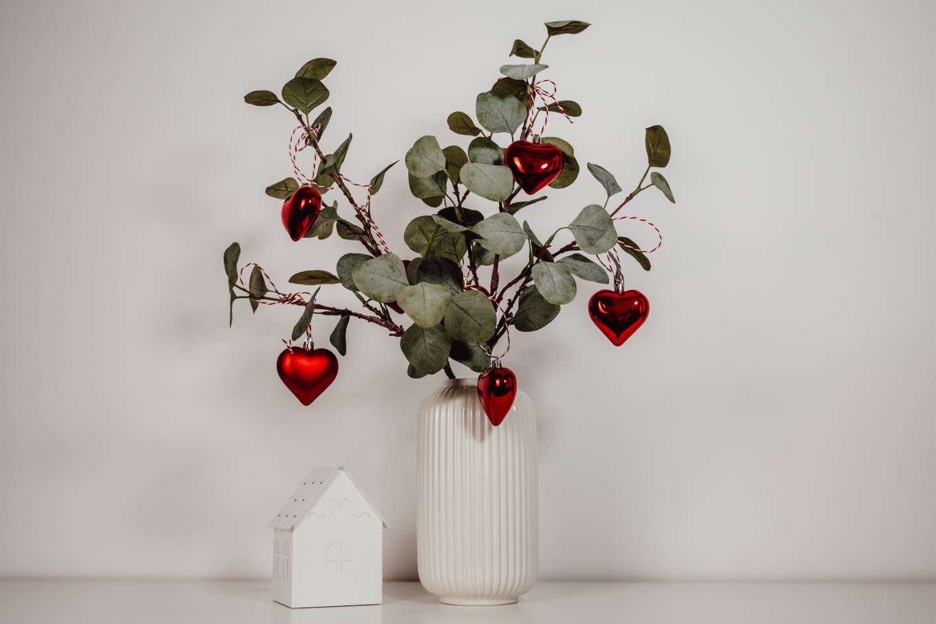 Eucalyptus branches decorated with red heart ornaments for christmas.