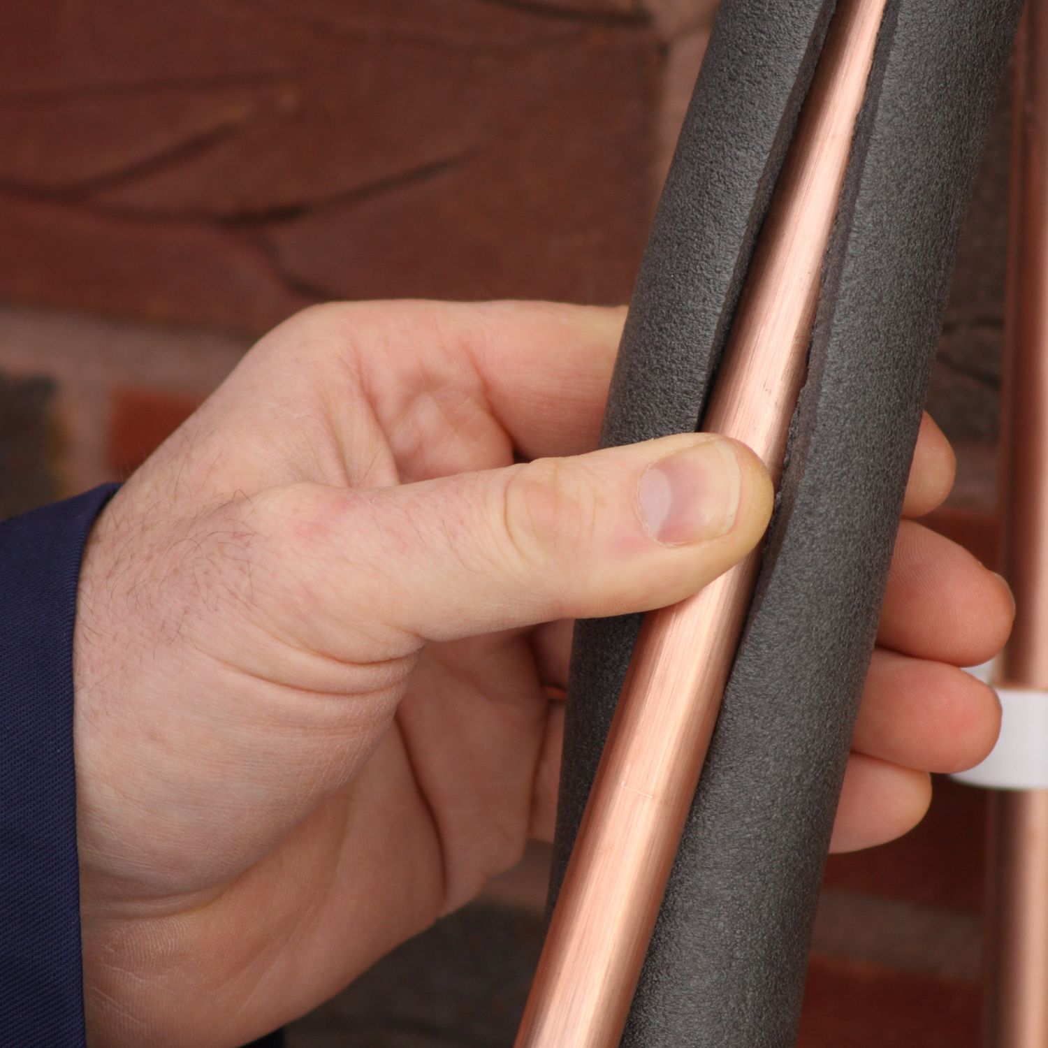 A Plumber demonstrating how to add insulation to a copper pipe to prevent freezing pipes. An easy DIY upgrade.