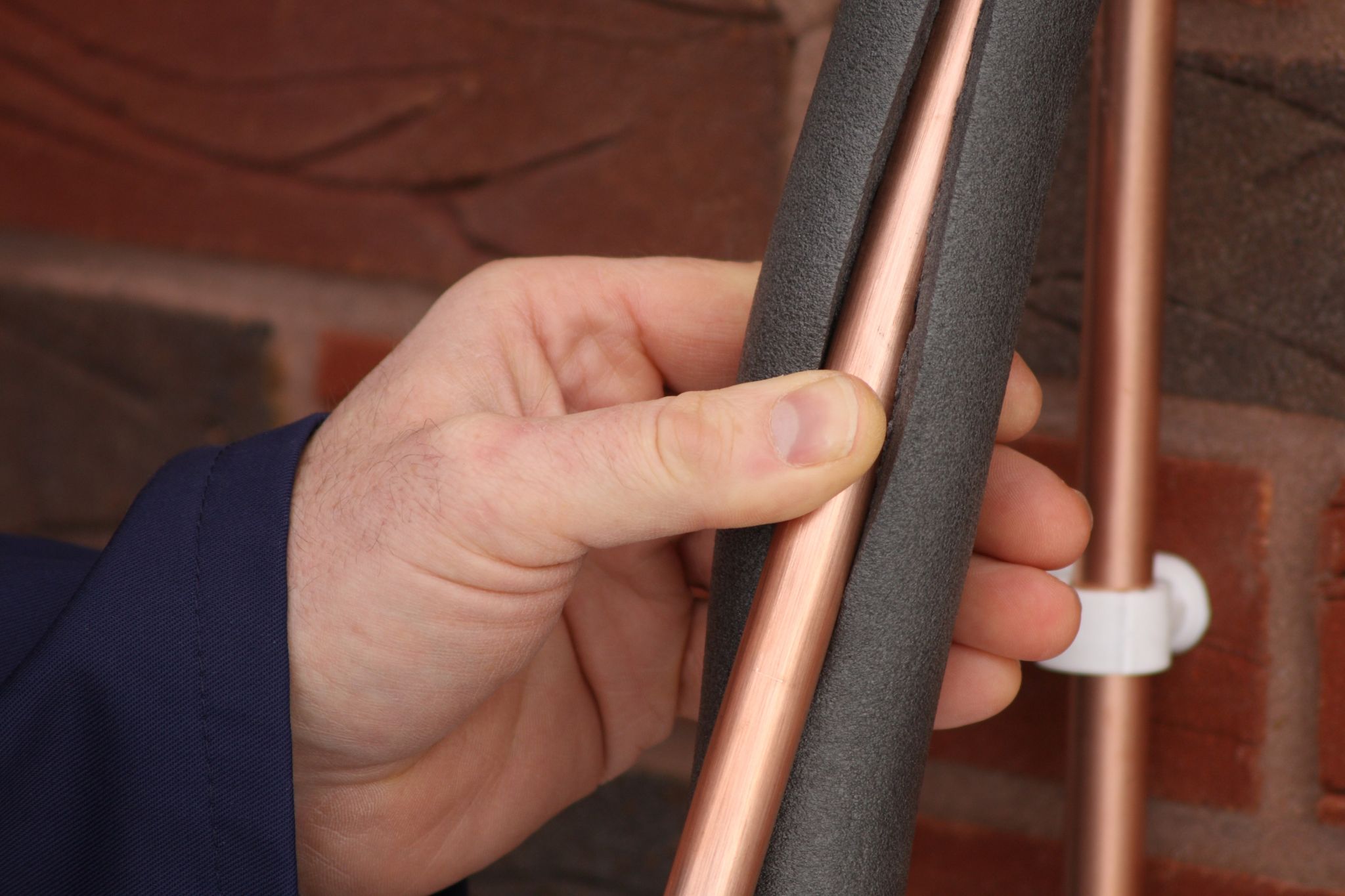 A Plumber demonstrating how to add insulation to a copper pipe to prevent freezing pipes. An easy DIY upgrade.