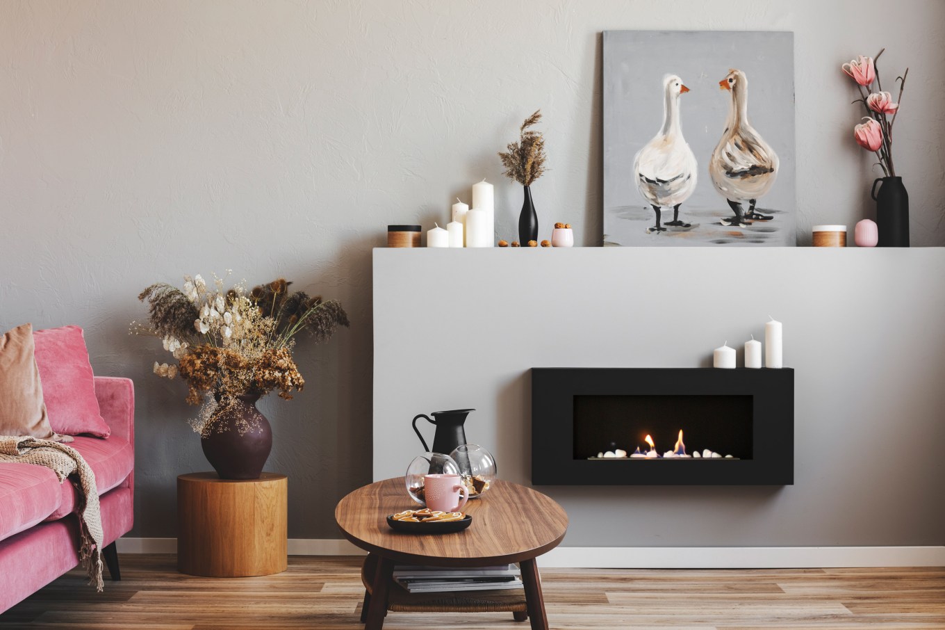 Elegant living room interior with black and grey ventless fireplace, wooden coffee table and pink couch