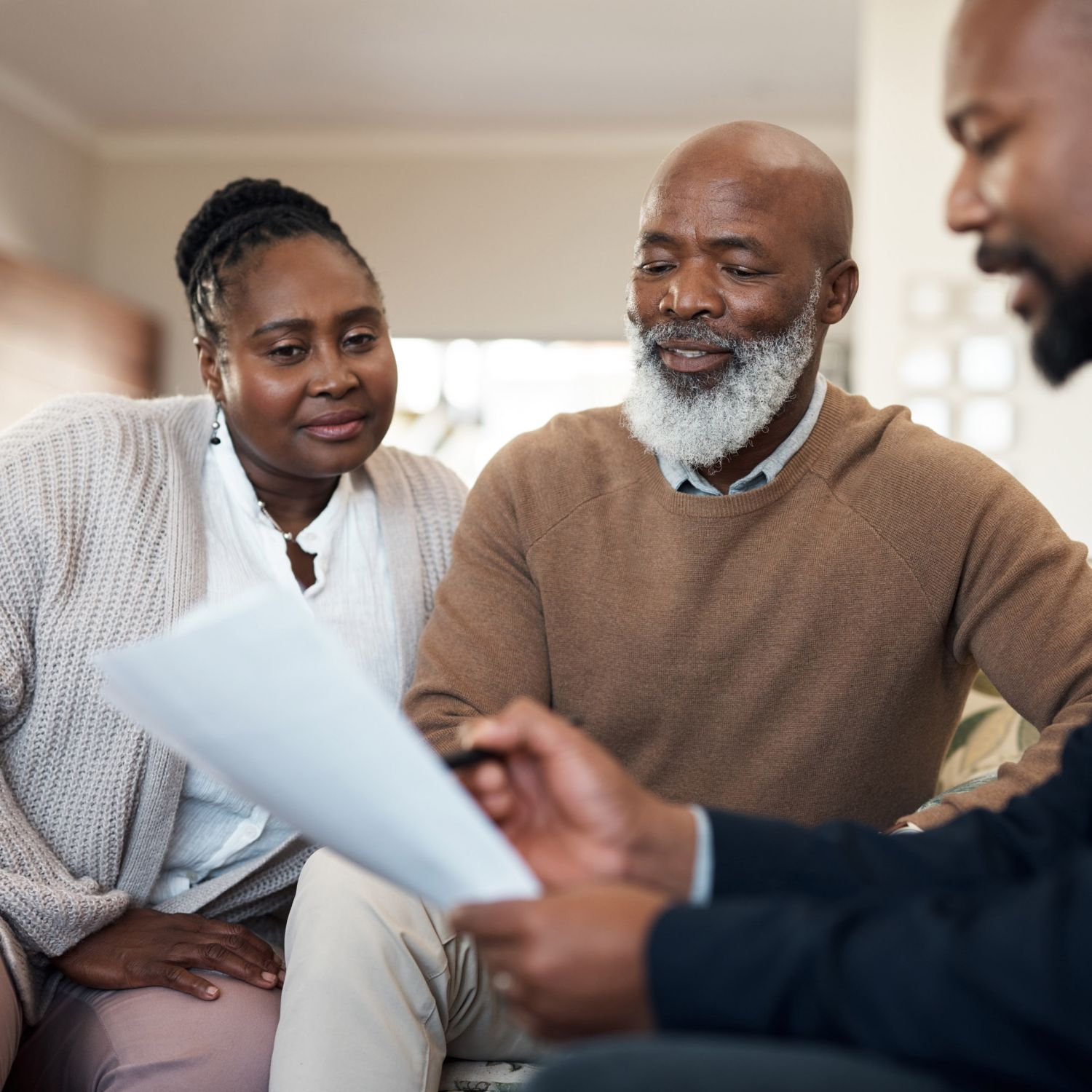 Mature, senior and married couple and a real estate agent looking over details of selling their house.