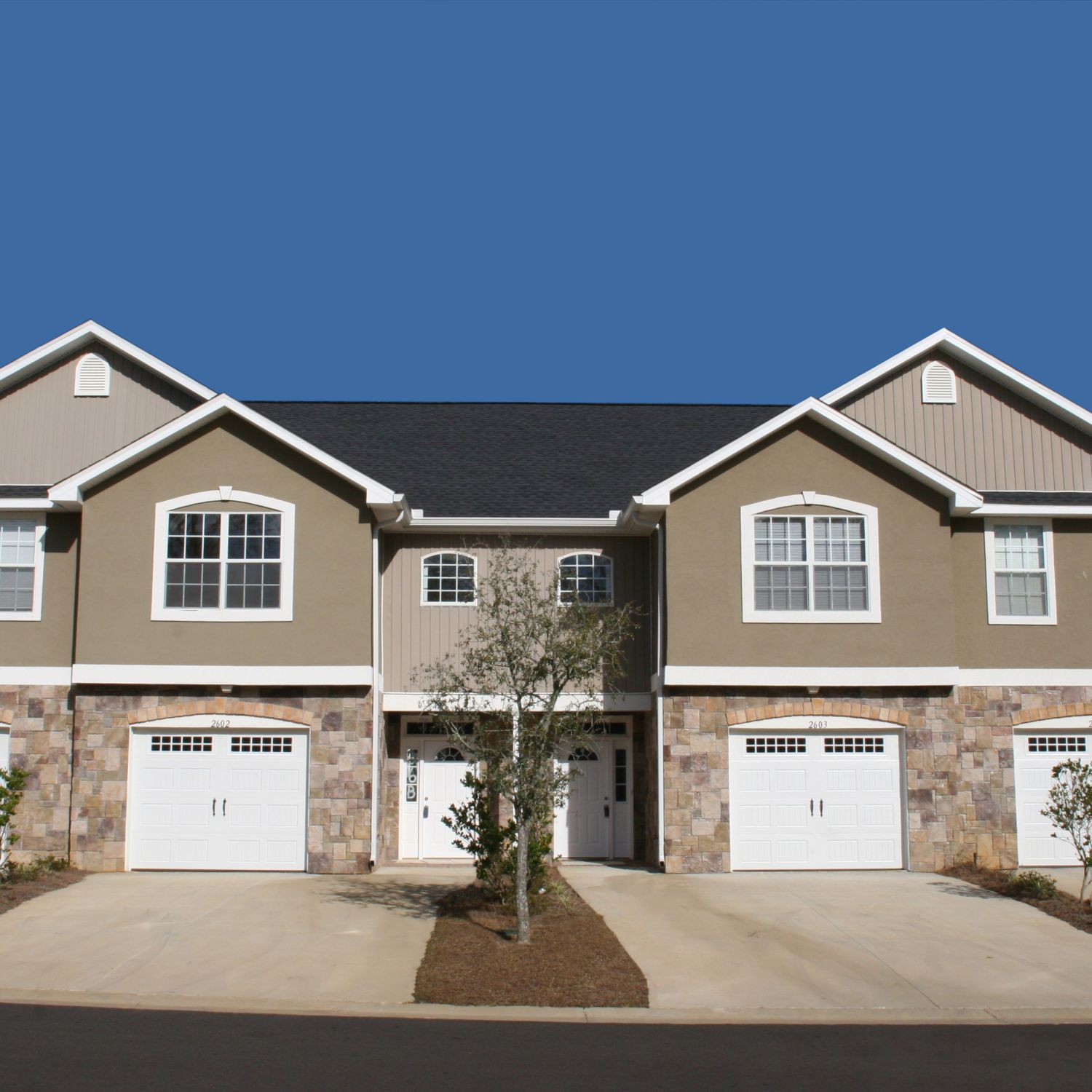 Newly constructed townhouse-style homes on clear sunny day.