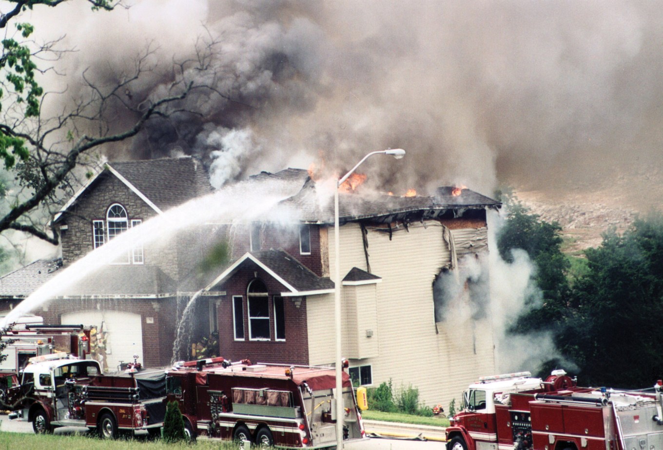 Firefighters putting out the last of a house fire caused by a small forest fire.